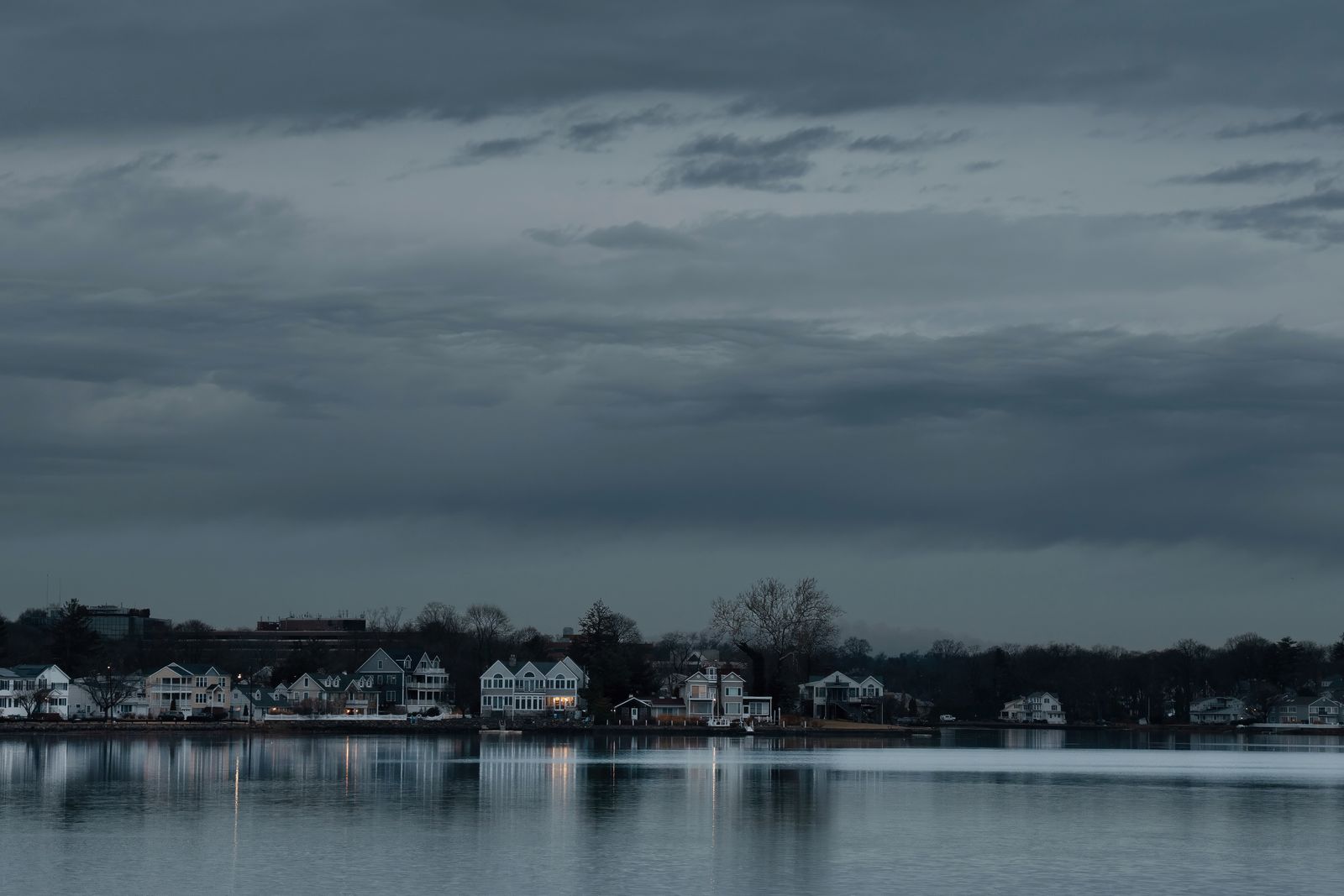 Stamford, Connecticut waterfront at dusk, homes and a modern building reflected on calm water under an overcast sky