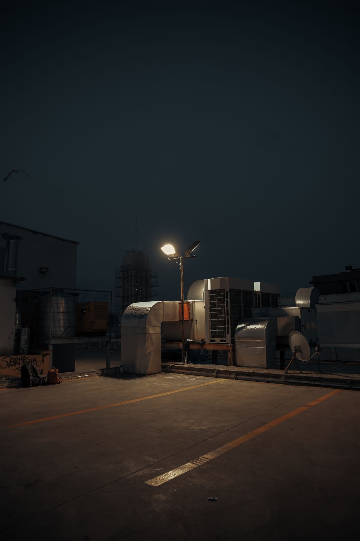 Rooftop HVAC and ductwork at night lit by a single work light